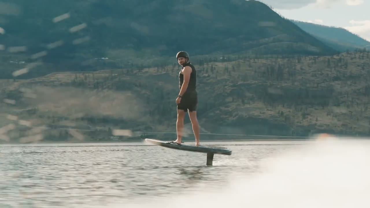 Efoil rider on open water, forested hills behind